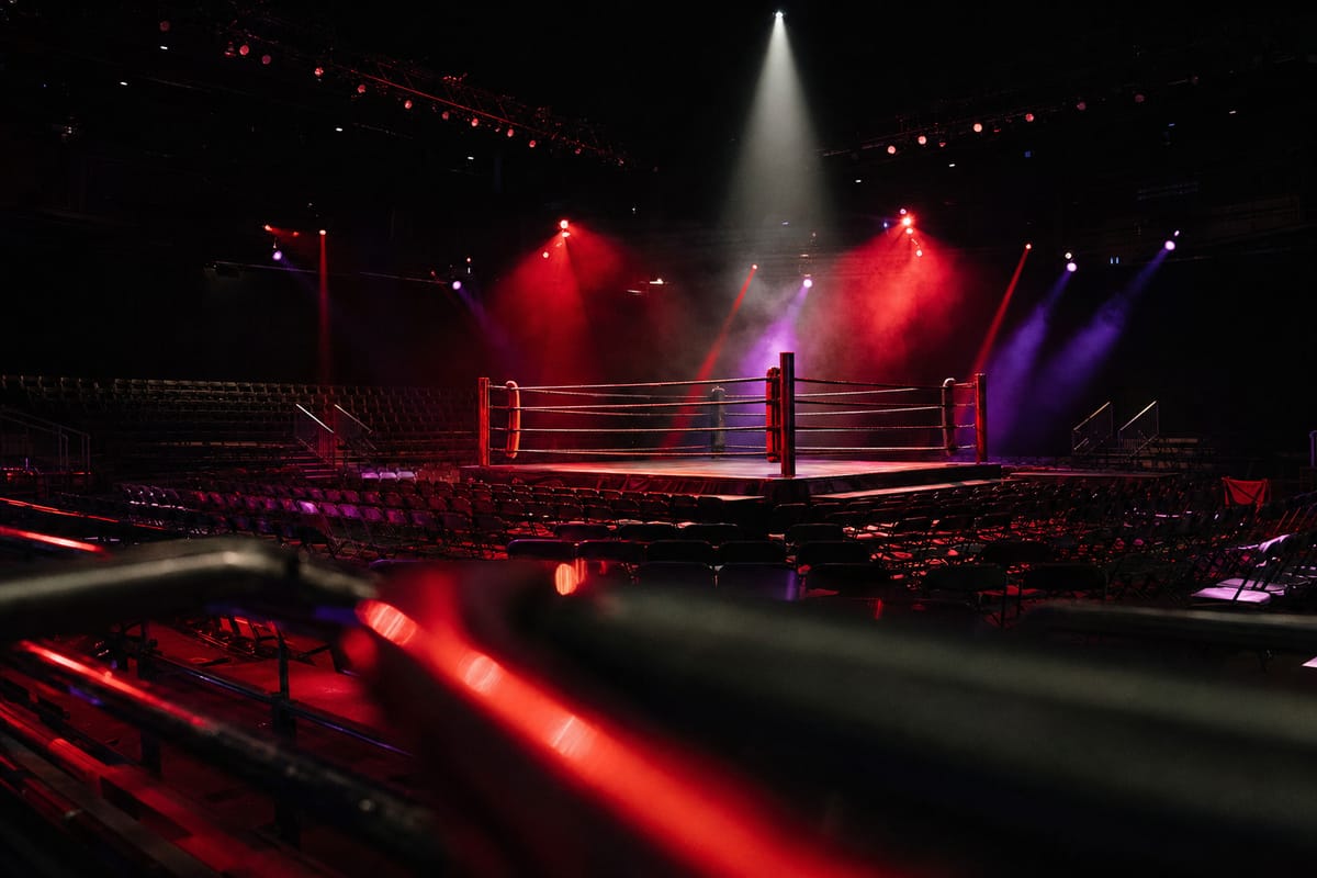 Empty arena set for a big event, a boxing ring under red and purple stage lights in haze (AI-generated image)