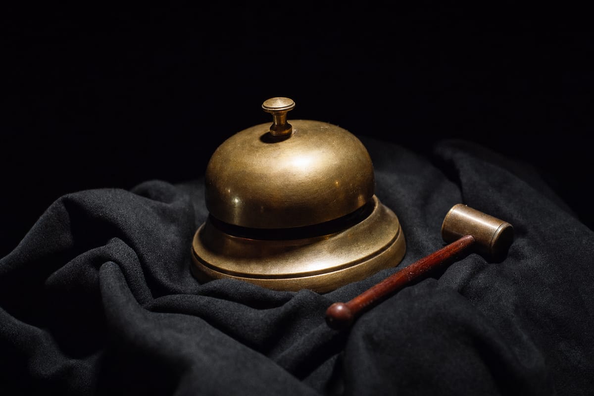 Brass boxing bell with its small hammer lying beside it on a black cloth under a spotlight (AI-generated image)