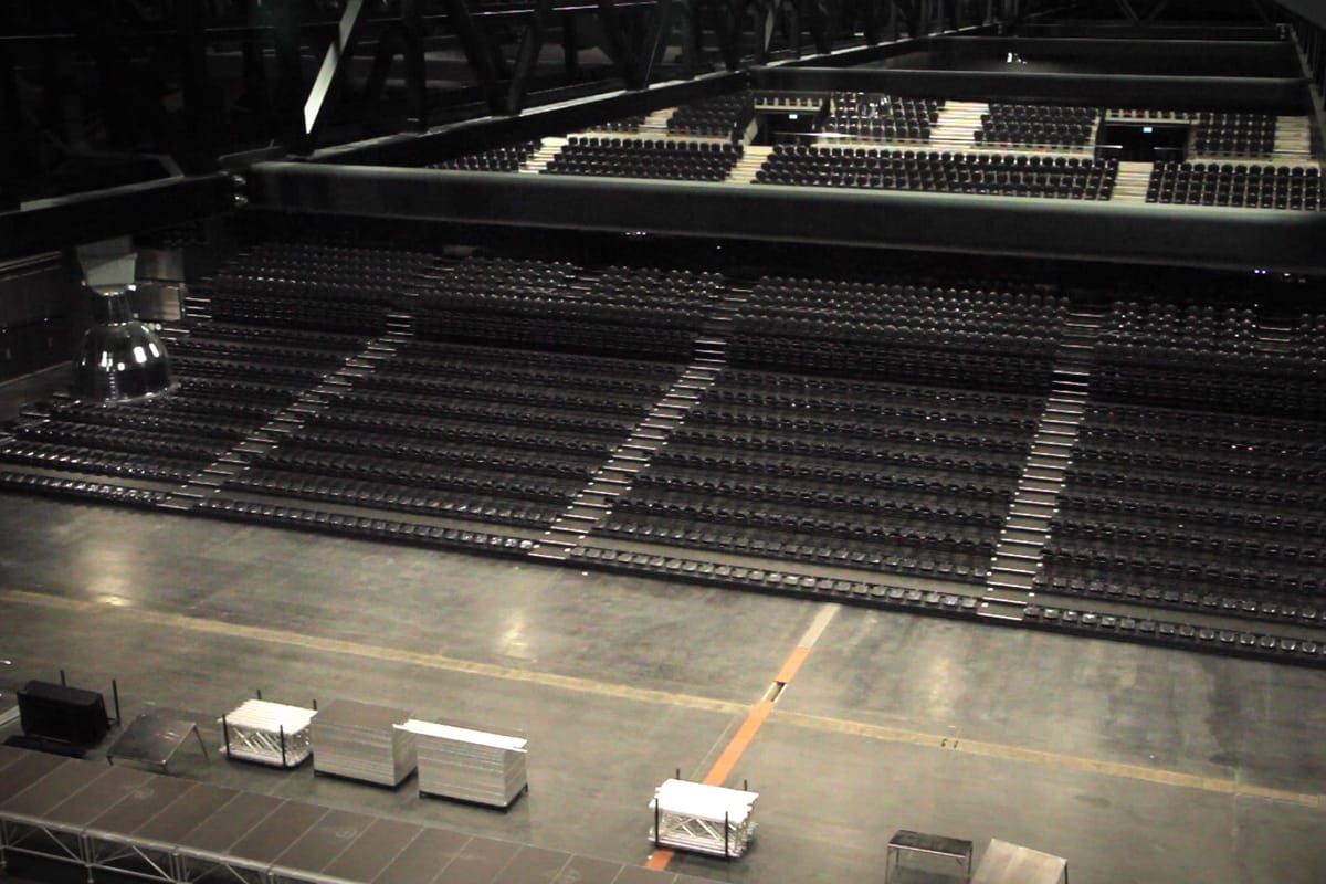 Black and white view from a balcony over an empty arena floor and rows of empty seats