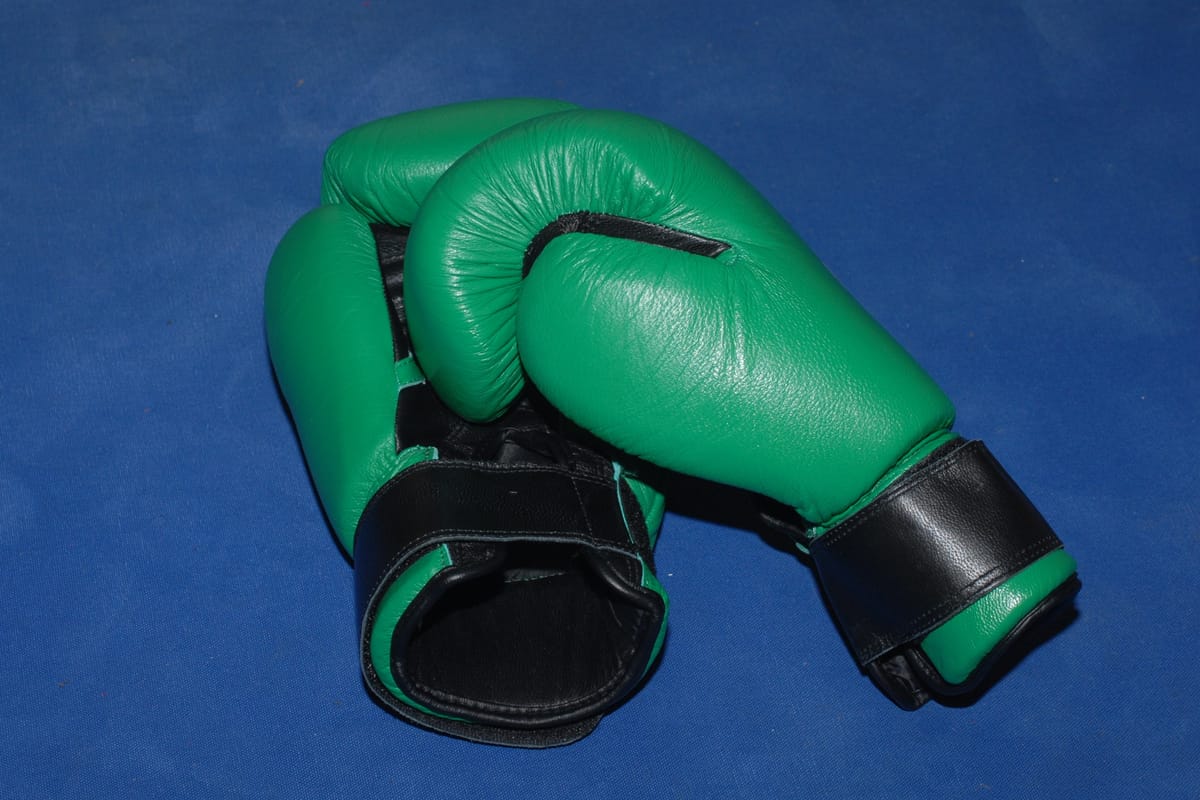 Pair of green and black boxing gloves lying on a blue surface